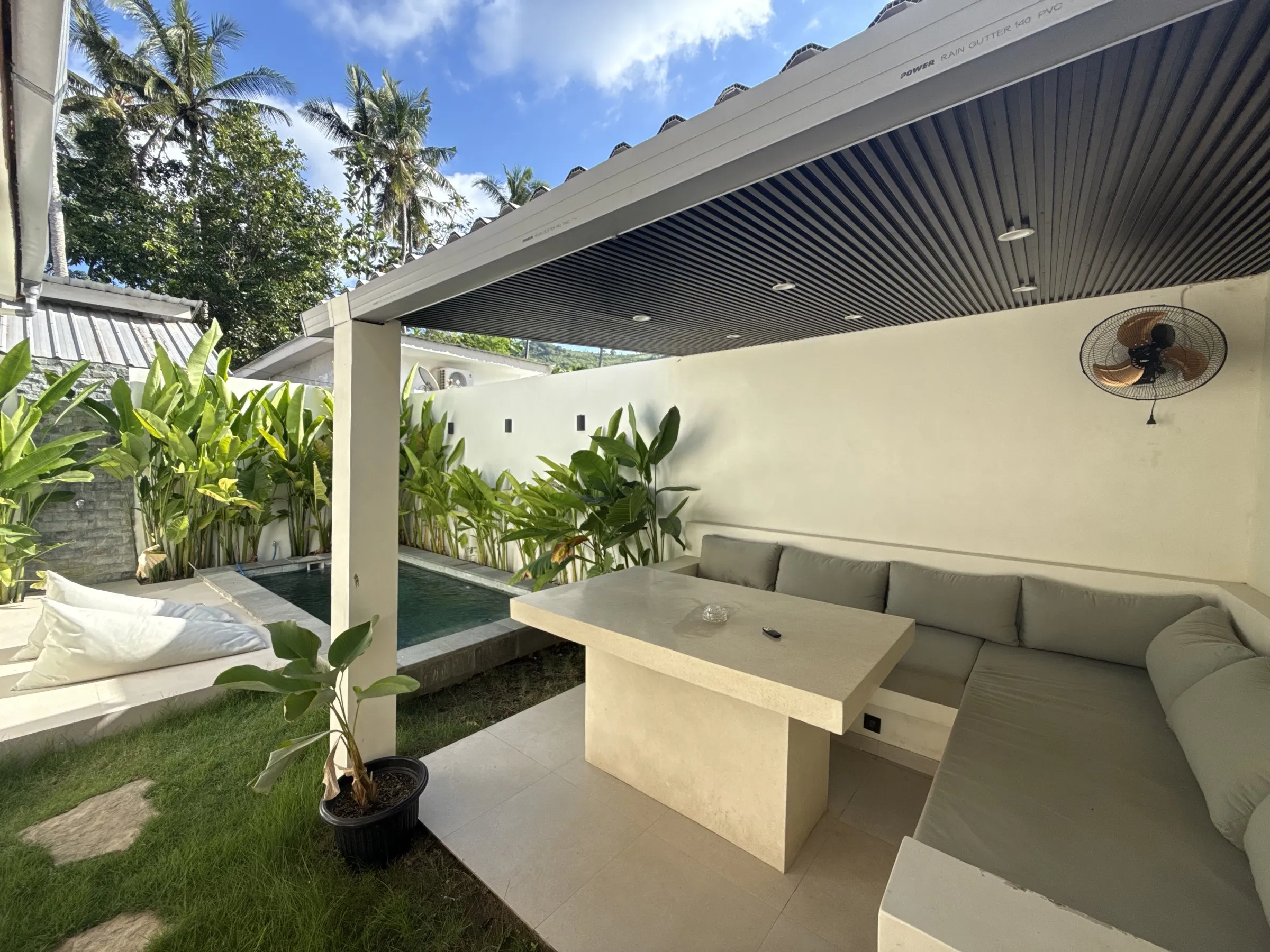 Covered outdoor lounge with a built-in sofa next to the pool
